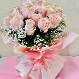 Bouquet of pale pink roses with white baby's breath in pink wrapping