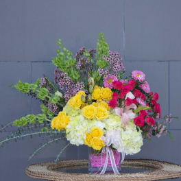 Mixed bouquet of yellow and pink flowers in a glass vase
