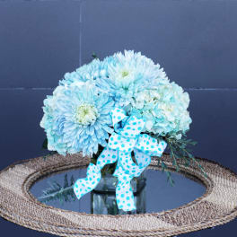 Blue and white flower arrangement in a glass vase with a polka-dot ribbon