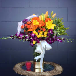 Colorful bouquet in a glass vase with a white ribbon
