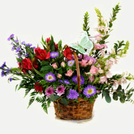 Basket arrangement of red, pink, and purple flowers with tall blooms