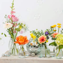 Colorful mixed flowers in small glass vases with a disco ball centerpiece