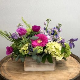Mixed bouquet with pink and purple flowers in a wooden box