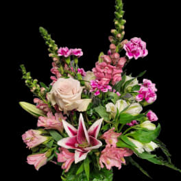 Pink and white mixed flower arrangement with a central lily in a vase