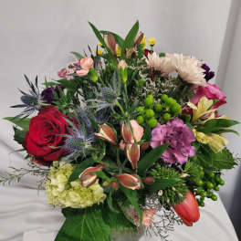 Mixed bouquet of roses, carnations, and lilies in a glass vase