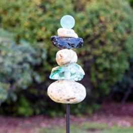 Stacked decorative stones on a metal stake in a garden
