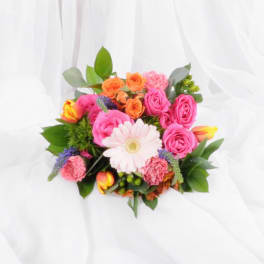 Bright mixed bouquet with pink gerbera, roses, tulips, and carnations on a white fabric backdrop