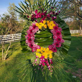 Large floral wreath with pink, yellow, and purple flowers on palm fronds