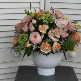 Pink and peach roses arranged in a white vase