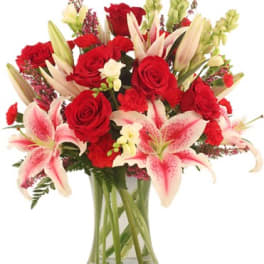 Bouquet of red roses and pink lilies in a clear glass vase