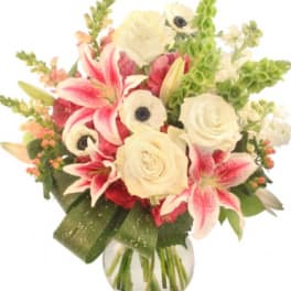 Bouquet of pink lilies, white roses, and white anemones in a glass vase
