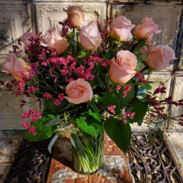 Peach roses in a clear glass vase with pink filler flowers