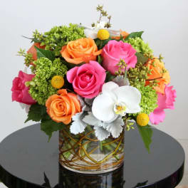 Mixed bouquet of pink and orange roses with white orchids in a clear glass cylinder vase