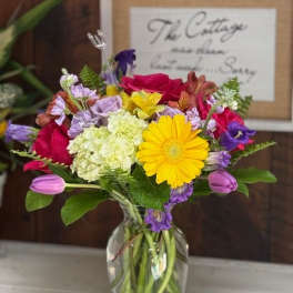 Mixed bouquet in a clear glass vase with yellow and pink blooms
