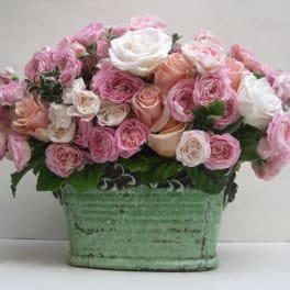 Pink and white roses arranged in a green ceramic container
