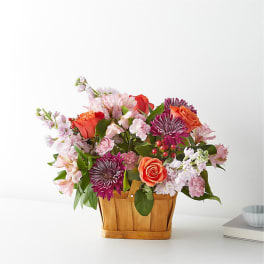 Mixed bouquet in a wooden basket with pink and orange flowers