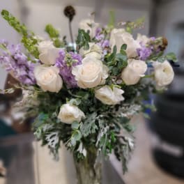 White roses and purple flowers arranged in a glass vase