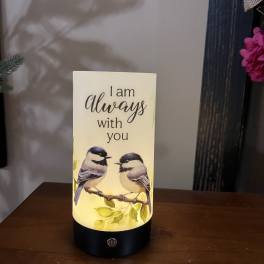 Lit memorial candle with two birds and the words "I am always with you"