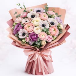 Bouquet of pastel flowers wrapped in pink paper with a satin ribbon