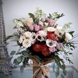 Mixed bouquet of pink, white, and red flowers in a burlap-wrapped vase