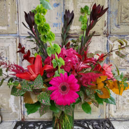 Bright mixed bouquet in a clear glass vase with pink and red blooms