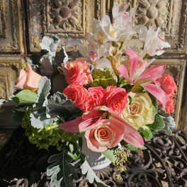 Bouquet of pink and cream roses with white orchids in a white vase