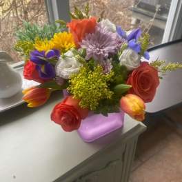 Colorful mixed bouquet in a lavender vase on a table