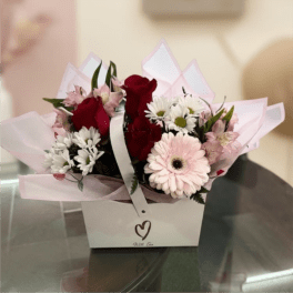 Bouquet of red roses, pink gerbera daisies, and white daisies in a gift box