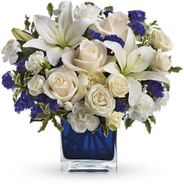 White lilies and roses arranged in a blue glass vase