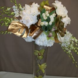 White floral arrangement in a tall glass vase with gold ribbon accents