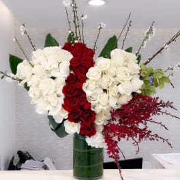 Tall arrangement of red and white roses in a glass vase
