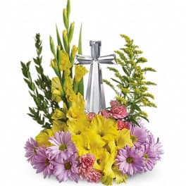 Yellow gladiolus and purple daisies arranged around a silver cross