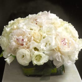 White bouquet of peonies and roses in a low container