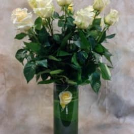 White roses in a tall green vase with a single rose on the front