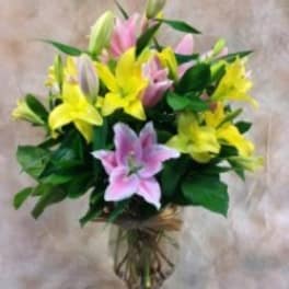 Bouquet of pink and yellow lilies in a glass vase