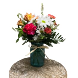 Mixed bouquet of daisies, carnations, and lilies in a blue glass vase