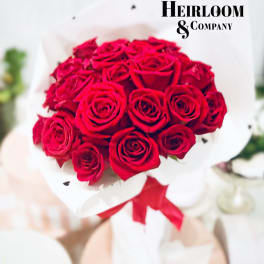 Bouquet of red roses wrapped in white paper with a red ribbon