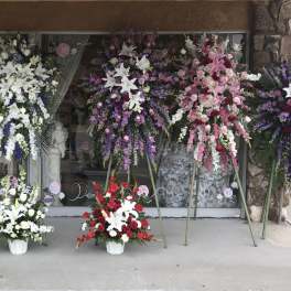 Large standing floral sprays in white, purple, pink, and red outside a storefront
