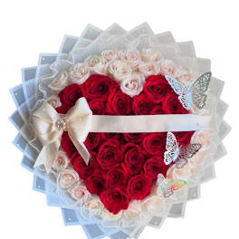 Heart-shaped bouquet of red and pale pink roses with a ribbon bow