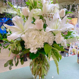 White lilies and hydrangeas arranged in a clear glass vase