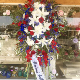 Standing funeral spray with red roses, white lilies, and blue flowers
