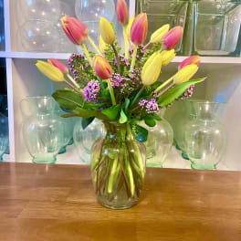 Pink and yellow tulips arranged in a clear glass vase