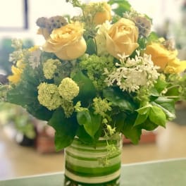Yellow roses and white filler flowers in a glass vase