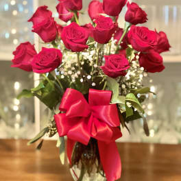 Bouquet of red roses in a glass vase with a large red ribbon