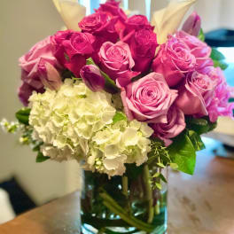 Pink and magenta roses with white hydrangeas in a glass vase