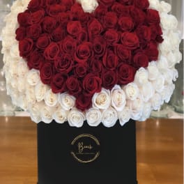 Heart-shaped red and white rose arrangement in a black box