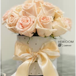 Peach roses arranged in a white polka-dot hatbox with a satin bow