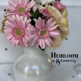 Pink gerbera daisies and carnations arranged in a white vase