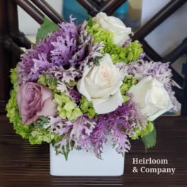 Bouquet of white and lavender roses with green hydrangeas in a white vase