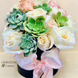 Bouquet of white roses and succulents in a black hatbox with a pink ribbon
